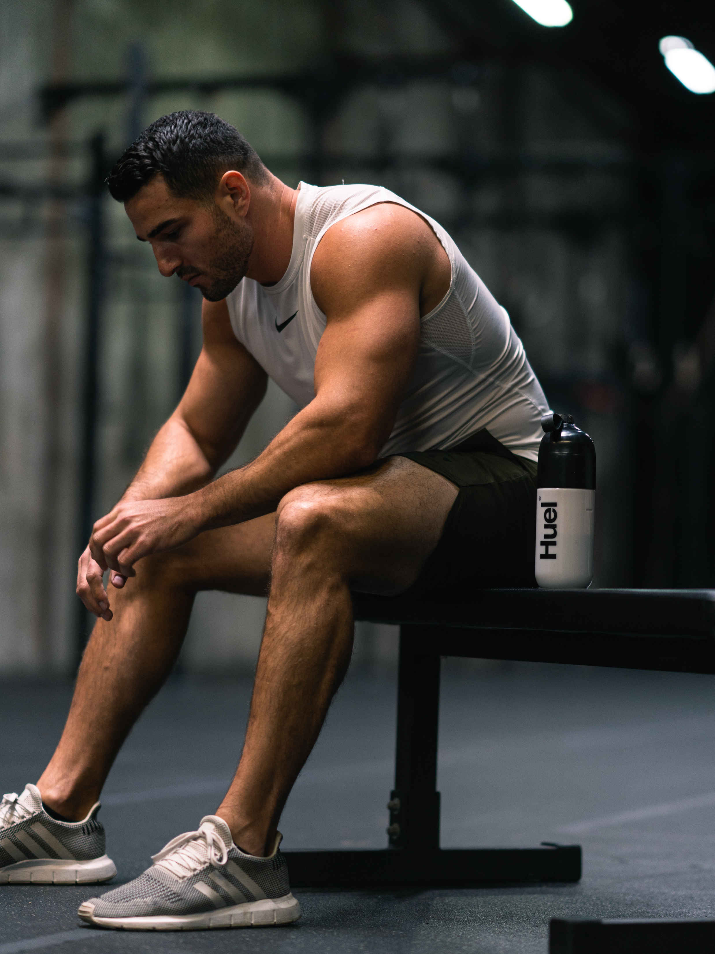 Athlete seated on a gym bench beside a Huel shaker